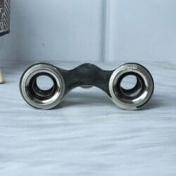 Close-up view of the eyepieces on a pair of nickel-plated antique pocket binoculars, showing the lens and frame.