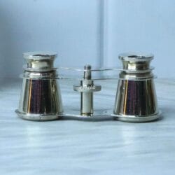 Direct front view of collectible nickel-plated theater binoculars, displaying the barrels and central focusing mechanism.