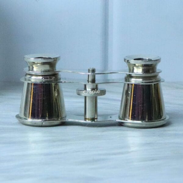 Direct front view of collectible nickel-plated theater binoculars, displaying the barrels and central focusing mechanism.
