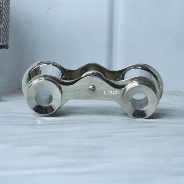 Top-down view of pocket-sized nickel binoculars, showing the shape of the bridge and the top of the focus knob.