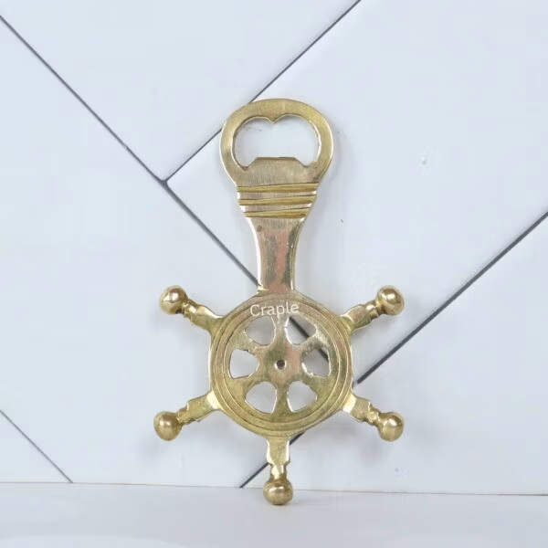 Solid brass ship's wheel bottle opener with a shiny finish, shown from a top-down view.