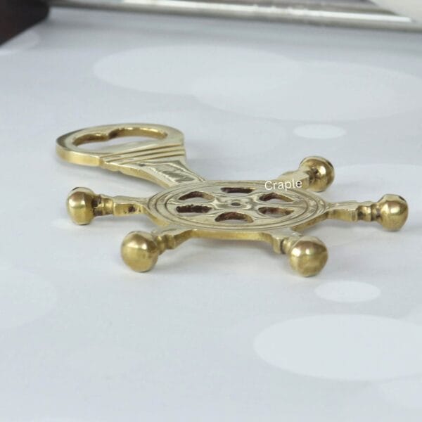 Angled view of the brass nautical helm bottle opener, highlighting its 3D design and sturdy construction.