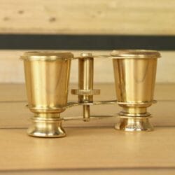 Side profile of collectible shiny brass binoculars, showcasing their traditional and elegant construction.
