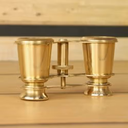Side profile of collectible shiny brass binoculars, showcasing their traditional and elegant construction.