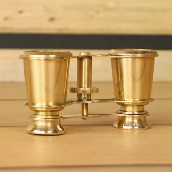 Side profile of collectible shiny brass binoculars, showcasing their traditional and elegant construction.
