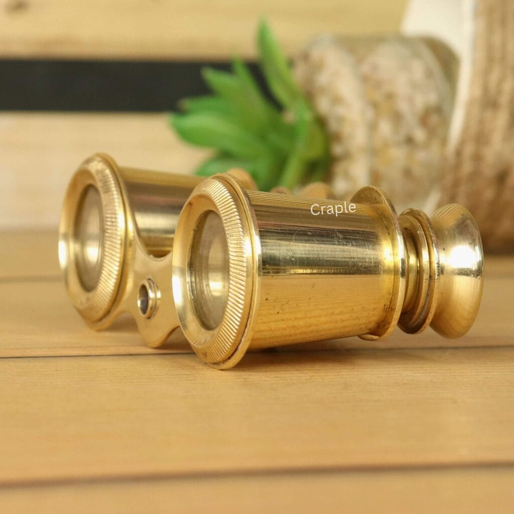 Detailed close-up side view of antique-style brass binoculars, highlighting the shiny finish on the eyepieces and barrels.
