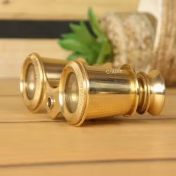 Detailed close-up side view of antique-style brass binoculars, highlighting the shiny finish on the eyepieces and barrels.