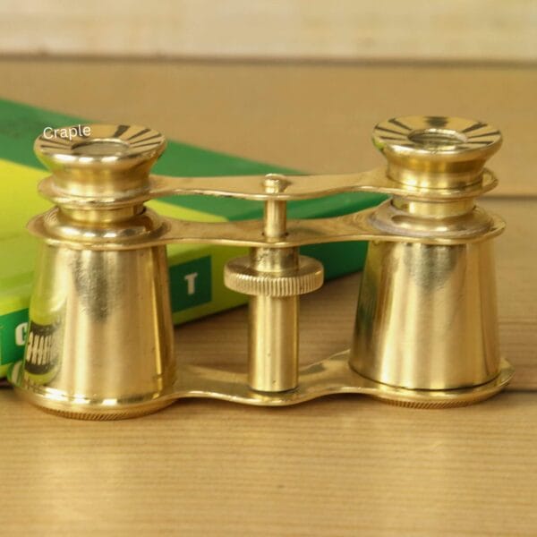 Shiny Brass Decorative Binoculars-4 Front view of compact Victorian-style brass theater binoculars with 2X magnification, resting on a green book.