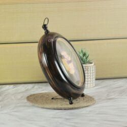 Side profile of the antique wooden clock, showing its deep circular frame, tabletop stand, and hanging loop.