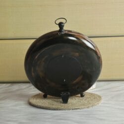 Rear view of the dark wood clock, showing the solid back panel and the base of its tabletop feet.