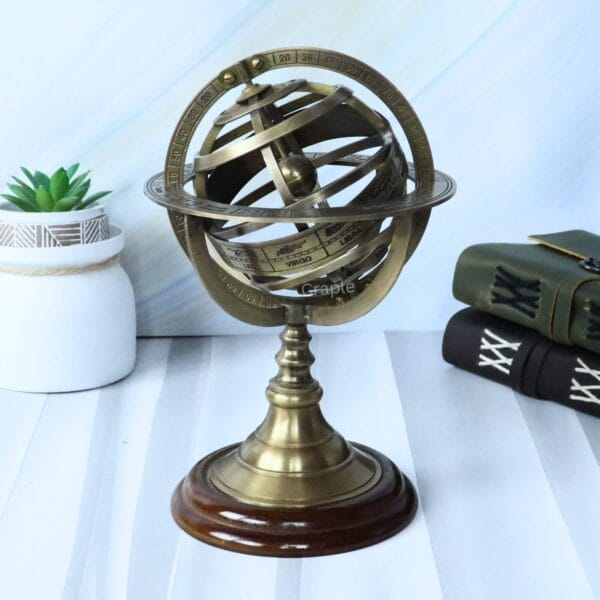 Front view of a brass celestial armillary sphere with an antique finish, sitting on a polished wood stand.