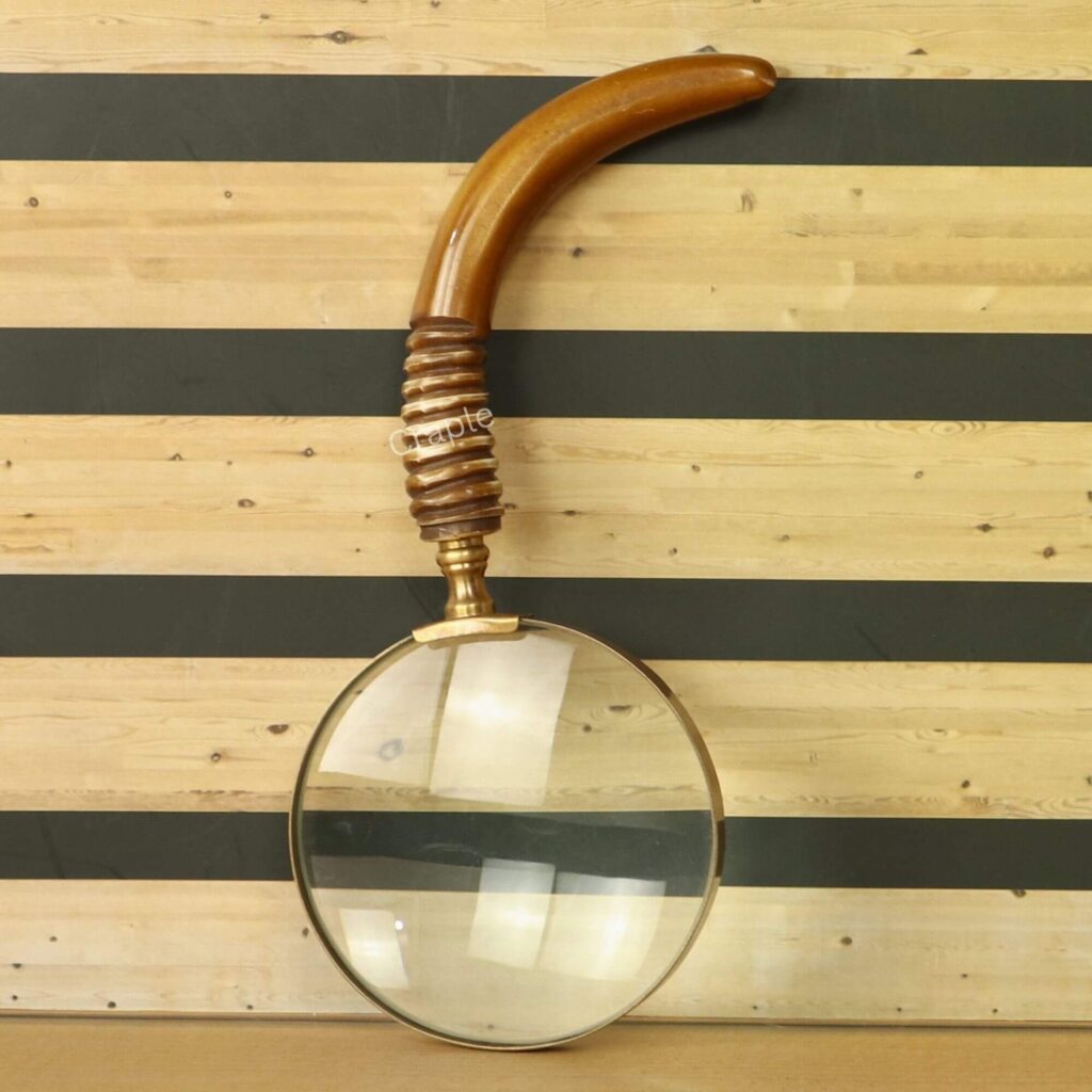 Antique brass magnifying glass with a large 5X lens and a uniquely curved wooden handle with a ribbed grip.