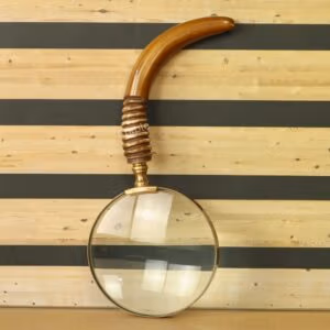 Antique brass magnifying glass with a large 5X lens and a uniquely curved wooden handle with a ribbed grip.