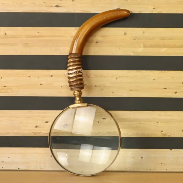 Antique brass magnifying glass with a large 5X lens and a uniquely curved wooden handle with a ribbed grip.