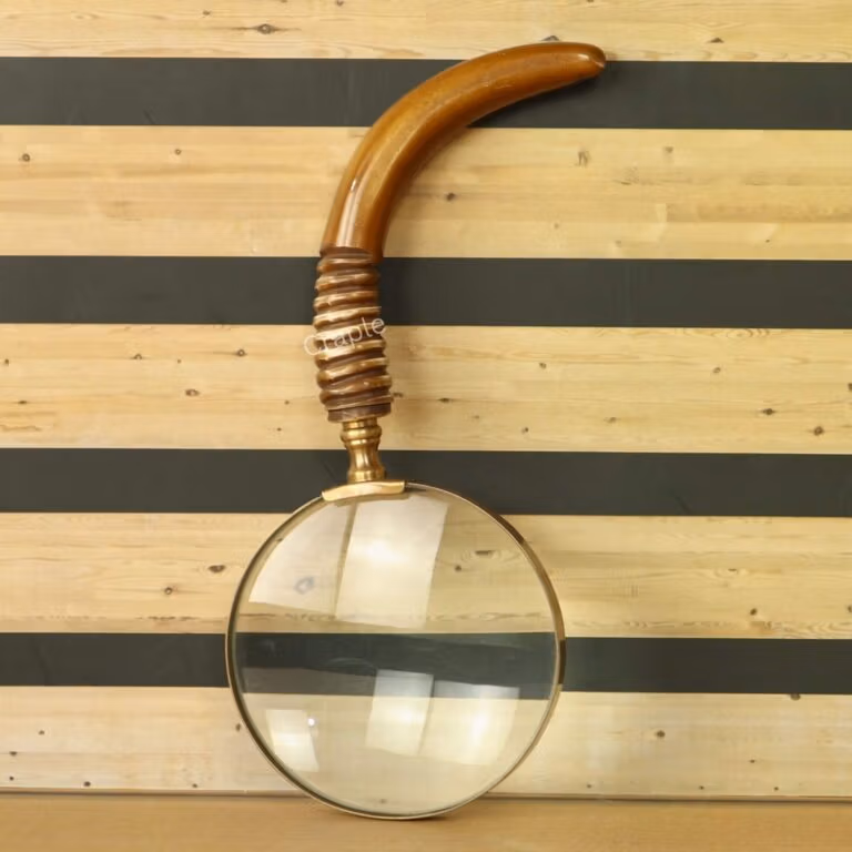 Antique brass magnifying glass with a large 5X lens and a uniquely curved wooden handle with a ribbed grip.