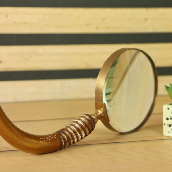 Close-up of the curved wooden handle of a vintage magnifying glass, showing the detailed ribbed carving on the grip.