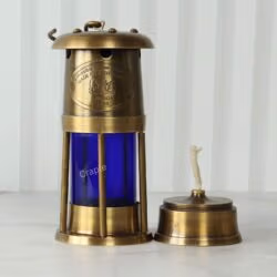 Brass mariner's lantern with its removable oil burner and wick placed next to it to show its function.