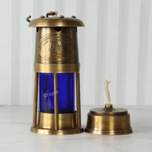 Brass mariner's lantern with its removable oil burner and wick placed next to it to show its function.