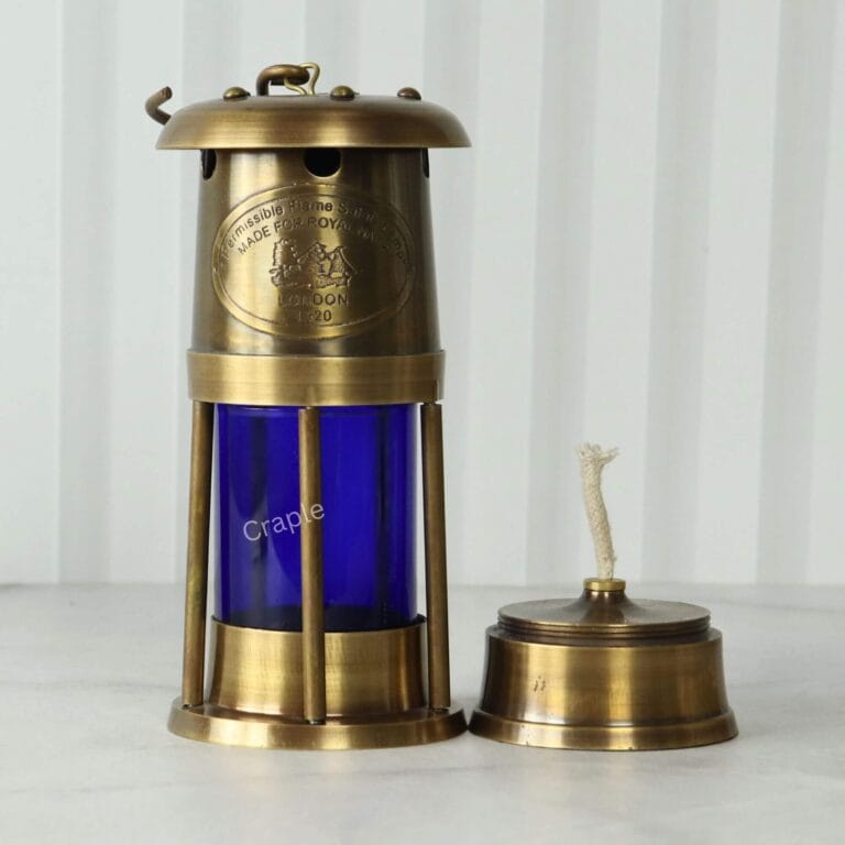 Brass mariner's lantern with its removable oil burner and wick placed next to it to show its function.