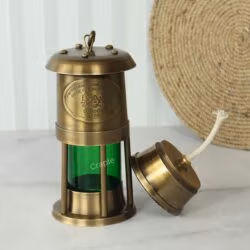The brass and green ship's lantern with the removable oil reservoir and wick placed beside the main body.