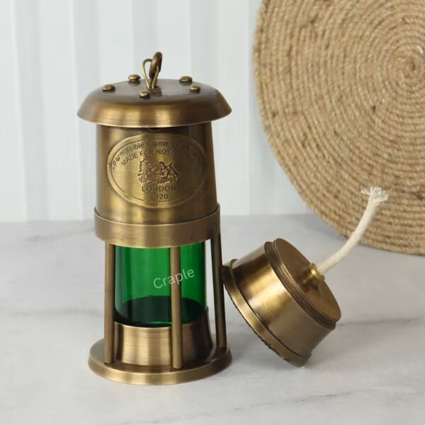 The brass and green ship's lantern with the removable oil reservoir and wick placed beside the main body.