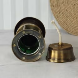 Top-down view into the green cylinder of the brass lantern, with the oil burner and wick component resting alongside.