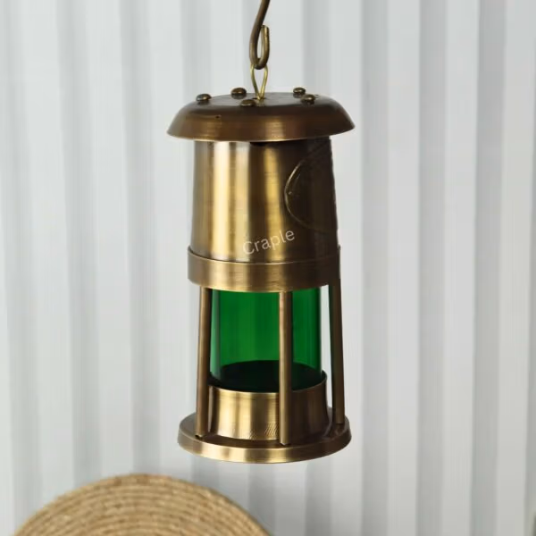 The brass nautical oil lantern hanging from its top hook, showcasing its use as a hanging light fixture.