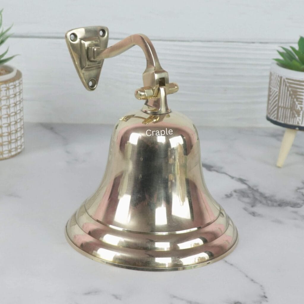 Wall-mounted solid brass nautical ship's bell with a shiny finish, complete with a traditional rope pull.