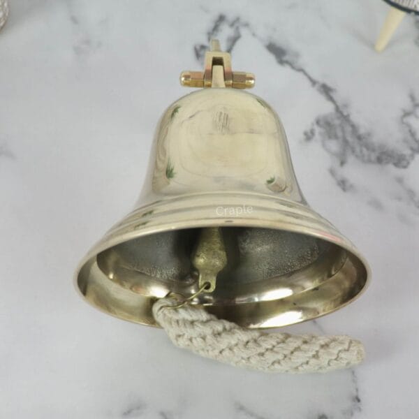Brass Nautical Ship Bell-4 View from underneath the large brass nautical bell, highlighting its wide mouth and the internal ringing mechanism.