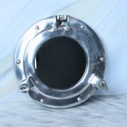 A round, nickel-finish porthole window frame shown in the open position against a wall.