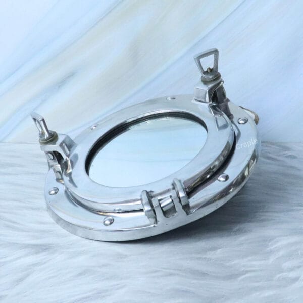 Angled side view of the nickel porthole mirror, detailing the sturdy hinge and closure mechanisms.