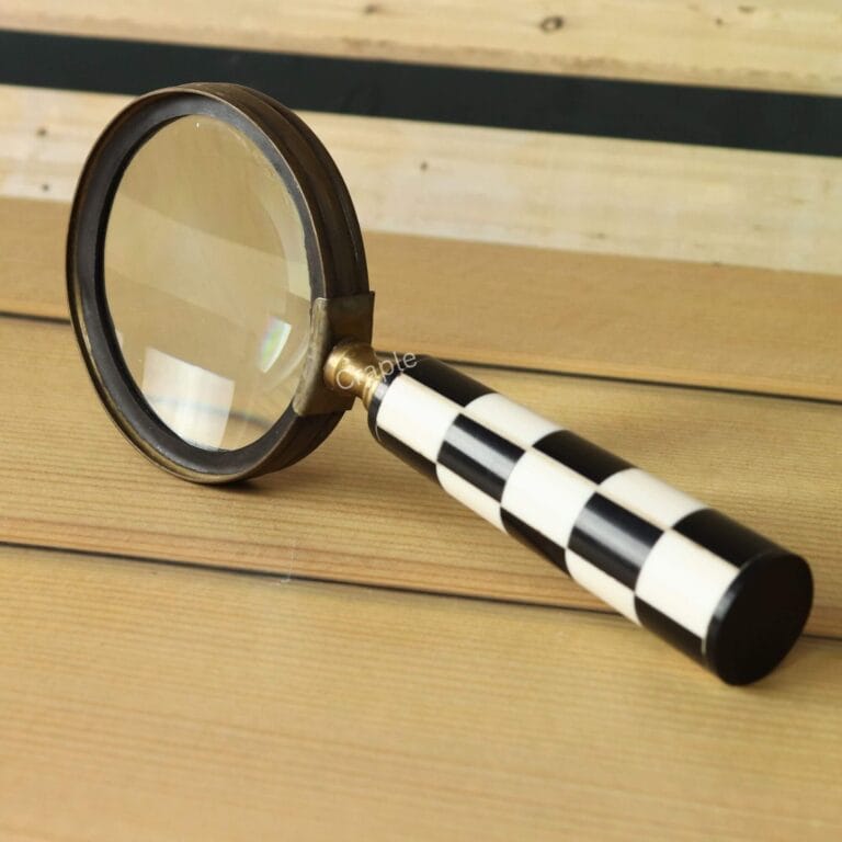 Handheld magnifying glass with a striking black and white chess pattern handle, an antique finish brass frame, and a 5X lens.