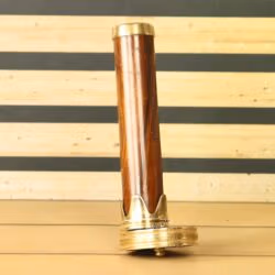 Full-length view of a vintage-style kaleidoscope with a wooden barrel and polished brass ends, standing upright on a table.
