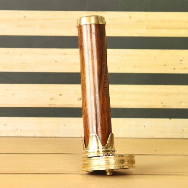 Full-length view of a vintage-style kaleidoscope with a wooden barrel and polished brass ends, standing upright on a table.