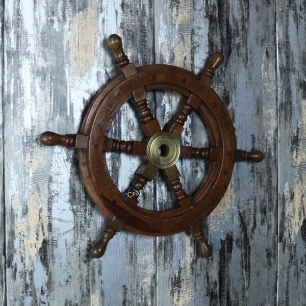 Angled view of the wooden captain's wheel hanging on a rustic wall, showcasing its texture and profile as wall decor.