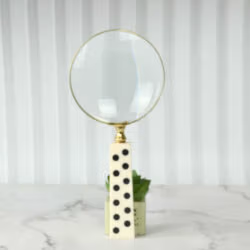 A domino handle magnifying glass standing upright on a desk, showcasing its design as a unique office accessory.