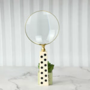 A domino handle magnifying glass standing upright on a desk, showcasing its design as a unique office accessory.