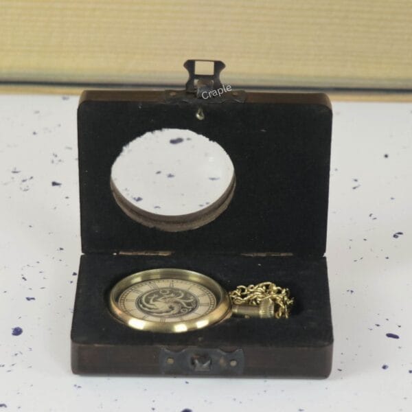 Dragon motif pocket watch with its chain displayed inside an open, dark wooden gift box with a clasp.