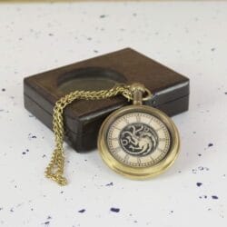 The fantasy-themed pocket watch and its antique brass chain resting against the dark wood presentation box.