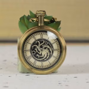 Close-up of an antique brass pocket watch featuring a three-headed dragon motif on the dial with Roman numerals.
