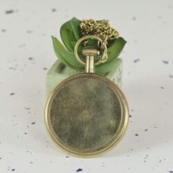 Rear view of the antique brass pocket watch, showing the brushed, non-engraved finish of the back case.