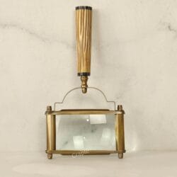 Top-down view of a rectangular page magnifier, showing the antique brass frame and the vertical fluted handle.