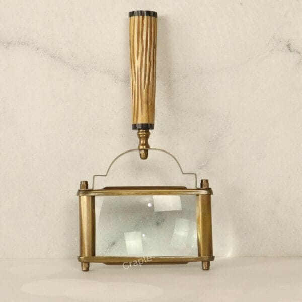 Top-down view of a rectangular page magnifier, showing the antique brass frame and the vertical fluted handle.