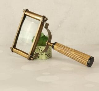 Vintage-style rectangular magnifying glass with a 5X lens, antique brass frame, and a textured fluted handle, resting on its side.