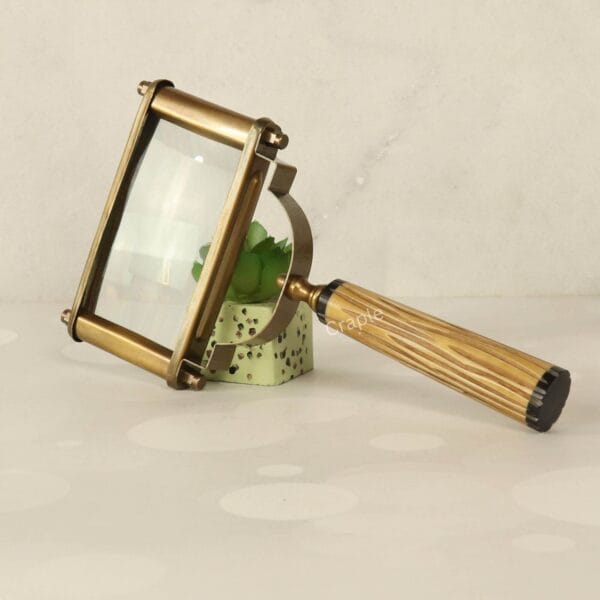 Vintage-style rectangular magnifying glass with a 5X lens, antique brass frame, and a textured fluted handle, resting on its side.