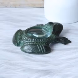 Side profile of the antique brass frog paperweight magnifier, showing its curved shape and three-dimensional details.