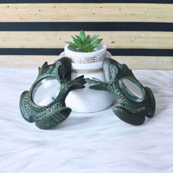 Frog Magnifying Glass-8 Two brass frog magnifiers displayed as decorative pieces with a small potted succulent in the background.