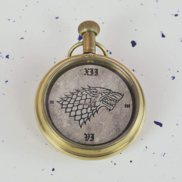 Close-up of the Game of Thrones pocket watch dial, showing the detailed Direwolf sigil and Roman numerals.