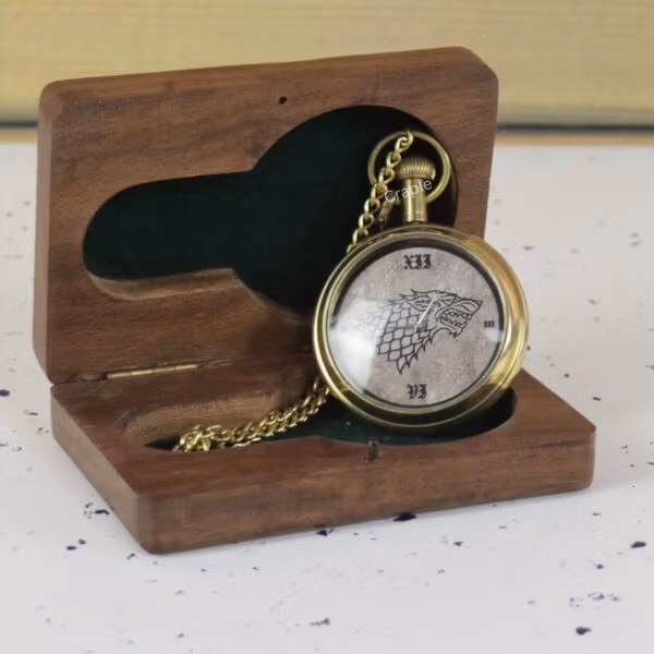 The Direwolf sigil pocket watch presented in an open, dark-wood gift box with a green felt interior.