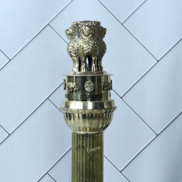 Close-up view of the Lion Capital of Ashoka on top of the brass pillar replica, showing the four lions.